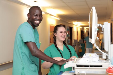Zwei Pflege-Auszubildende am Computer auf dem Stationsflur